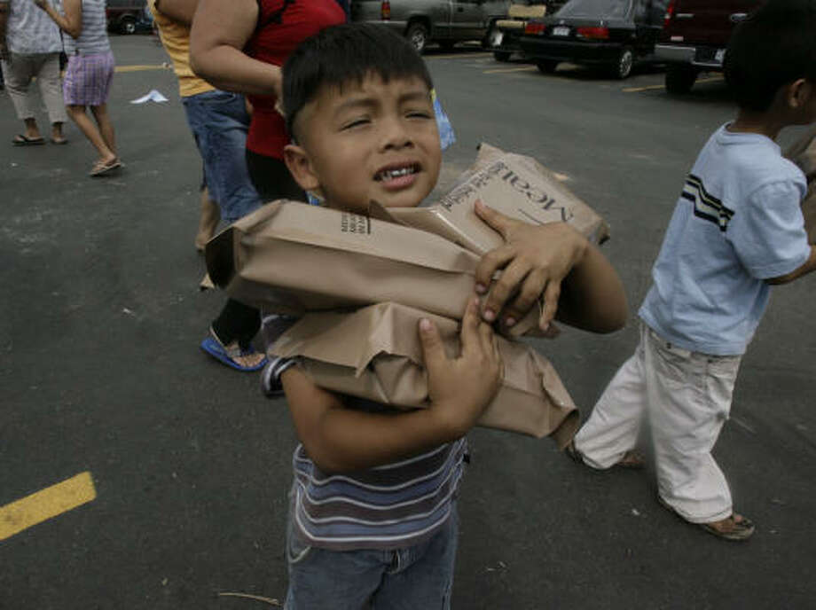 Safekeeping | Steven Merlos, 3, tries to keep a tight grip on the MREs that his family got from a FEMA distribution site set up at the Willow Creek Apartments. |Sept. 18 | Houston Photo: Julio Cortez, Houston Chronicle