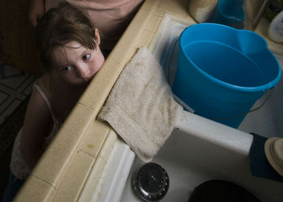 No water | Kloey Spahni, 5, stands at the sink where her mom washes dishes with water carried in a bucket. The Spahnis were among the tens of thousands of people in the area still without running water. | Sept. 23 | Houston Photo: Steve Ueckert, Houston Chronicle