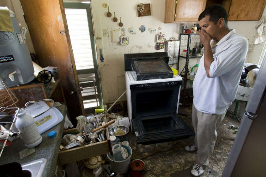 In shambles | Rolando Garza takes a break from cleaning his moldy and muddy kitchen. Garza said his family lost everything after floodwaters surged into his home. | Sept. 23 | Galveston Photo: Brett Coomer, Chronicle