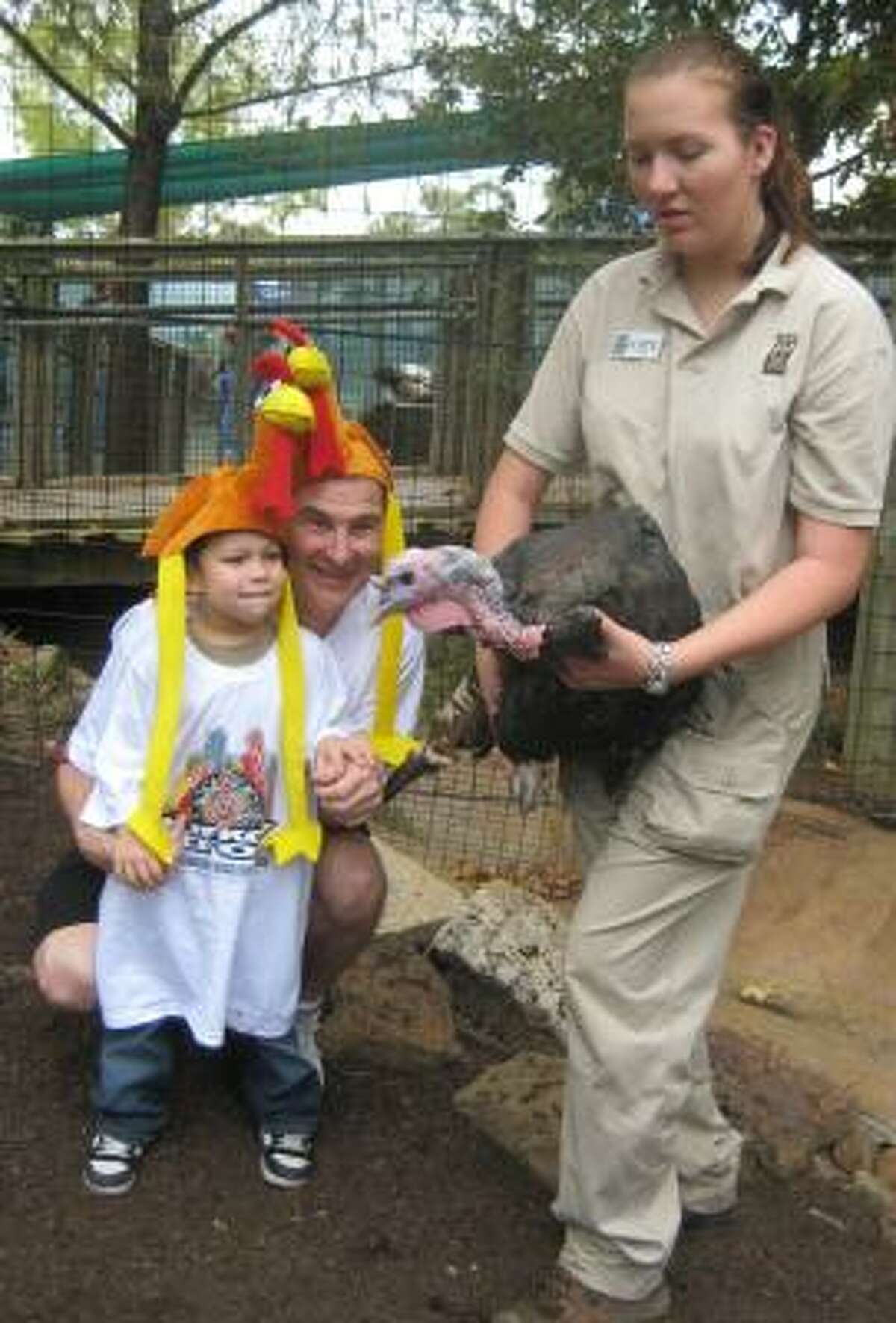 Robert Bass and his grandson Ivan Gutierrez look at a turkey held by Houston zoo employee Kate Balthaser after they won the zoo's turkey-calling contest.