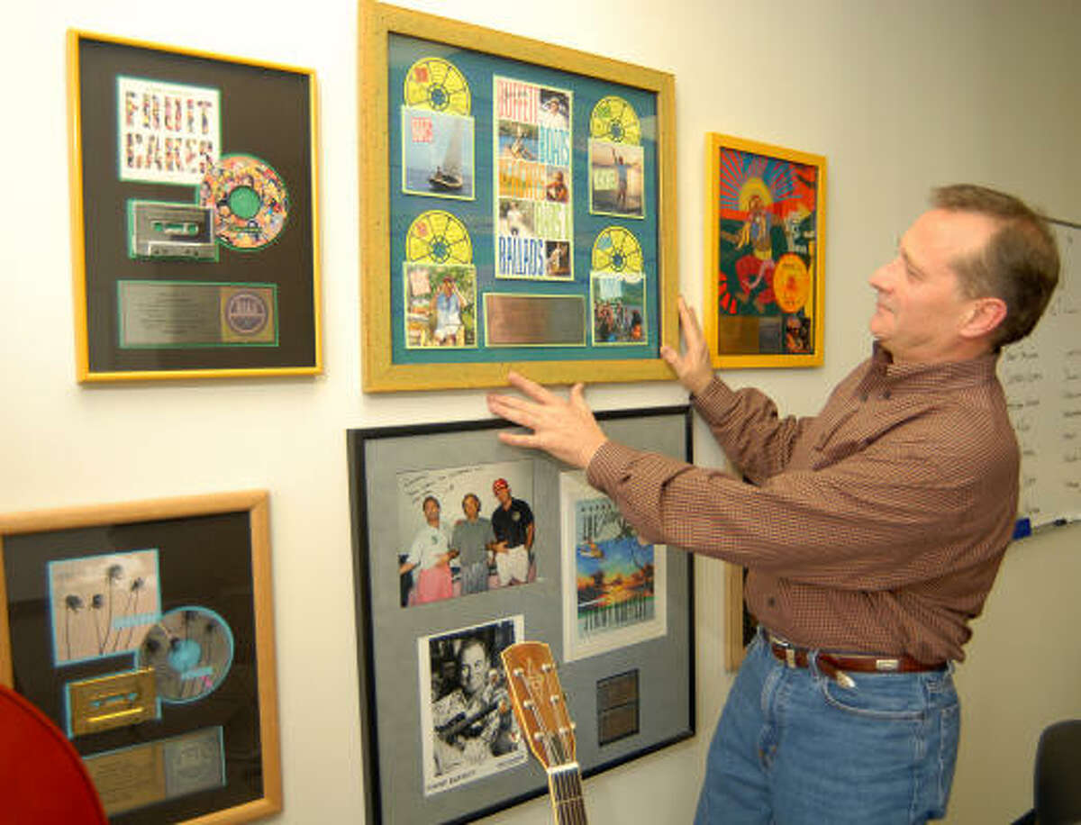 Coleman Sisson adjusts some framed Jimmy Buffett memorabilia in his Woodlands office. As the CEO of BubbleUp Media in The Woodlands, Sisson and his team design and create Web sites for major label recording artists, including Jimmy Buffett, Big & Rich and Gretchen Wilson.