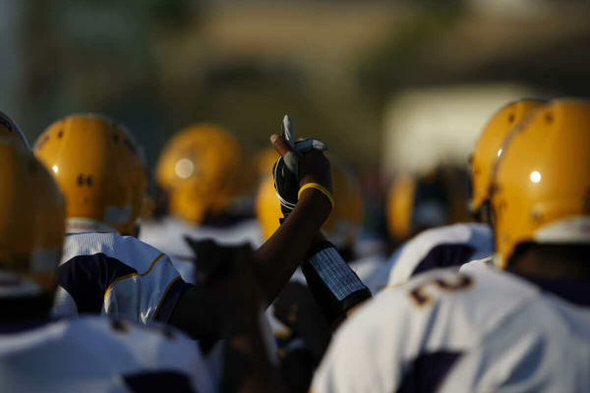 Ball High School football players hold hands as they march onto the field before their game against Clear Creek.