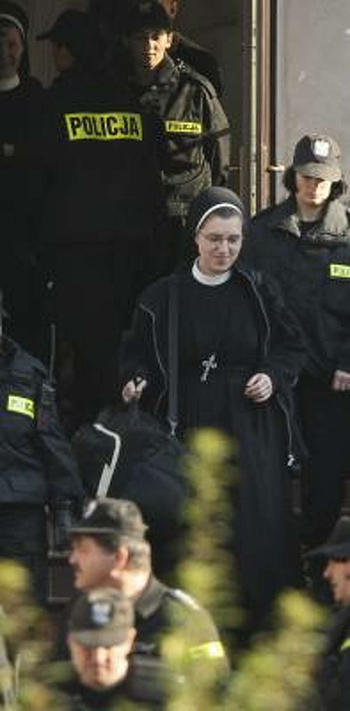A former nun is escorted from the eastern Poland convent on Wednesday.