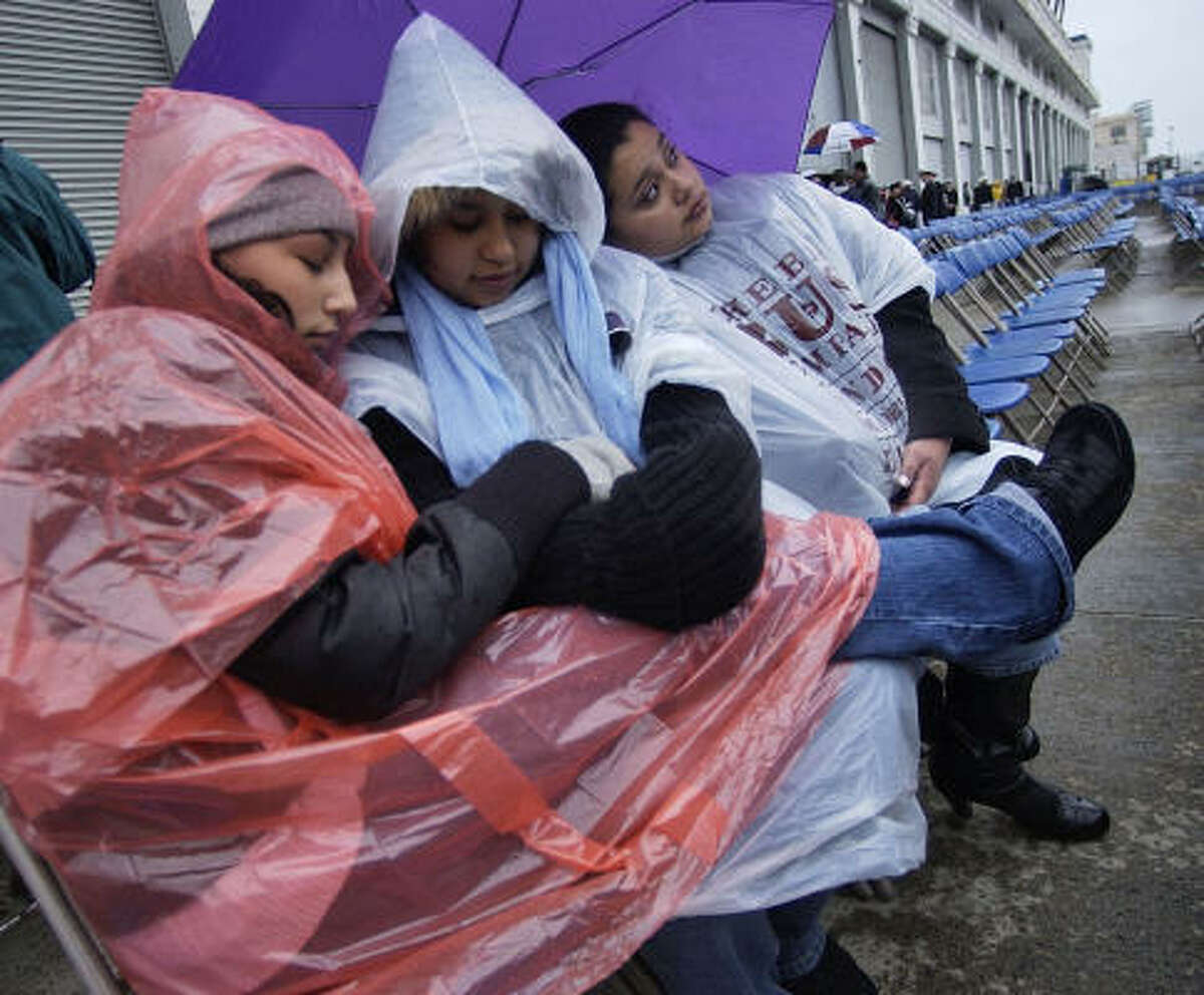 New England faces the remnants of Hurricane Noel. Vanessa Nunez of Turlock, Calif., left, Elizabeth Paz of Newport News, Va., and Jessica Paz of Quantico, Va., wait in the rain for the start of the commissioning ceremony Saturday for the guided-missile destroyer USS Sampson in Boston.