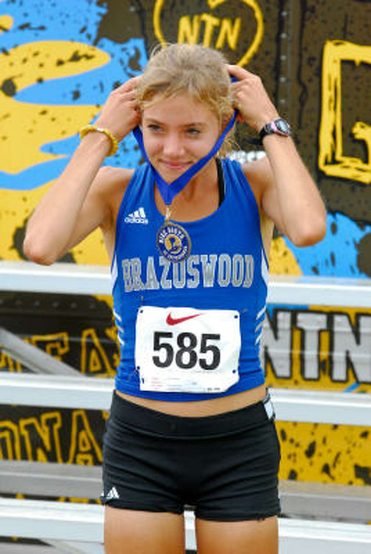 Brazoswood junior Lauren Smith slips the first-place Nike South medal over her neck after winning the 5K race.