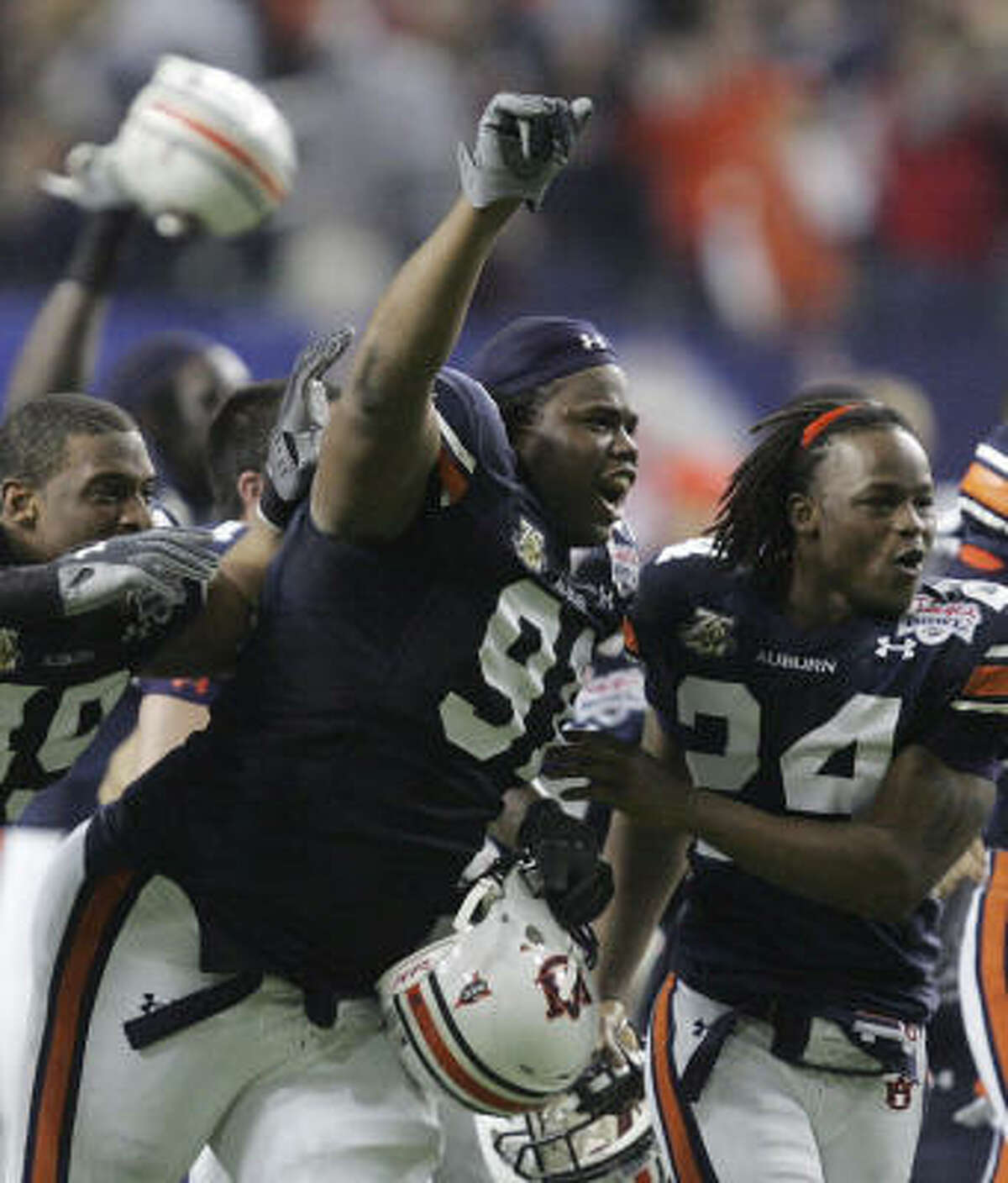 Auburn's Michael Goggans (49), Jake Ricks (91) and Jonathan Wilhite (24) storm the field after Kodi Burns scored a touchdown in overtime to give Auburn a 23-20 win over Clemson in the Chick-fil-A Bowl.