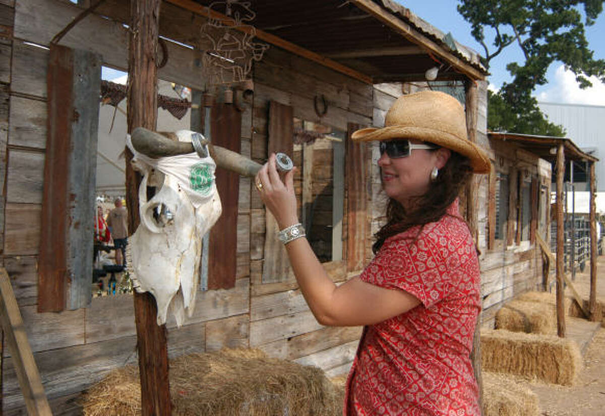 Magnolia's Gari Hessong, a member of the Cedar Creek Social Club, places washers on the horns of a skull to be used for a game like horseshoes. The elaborate false front of the club's wooden saloon was set up in the 2006 Montgomery County Fair barbecue cook-off.