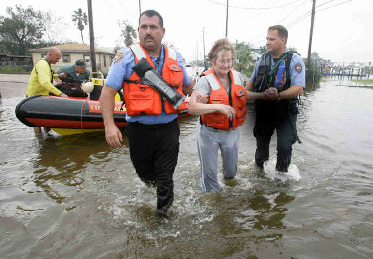 Dolores Gabriles, 71, is helped from a rescue boat by police captain Walter Braun, left, and officer Jeremy Smart in Galveston.