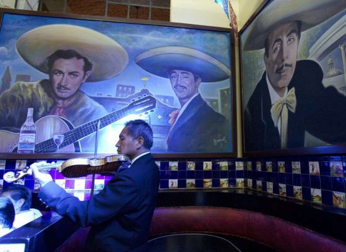 Surrounded by several colorful murals, a mariachi violinist plays for tourists and locals at the Tenampa bar in Mexico City's Plaza Garibaldi.