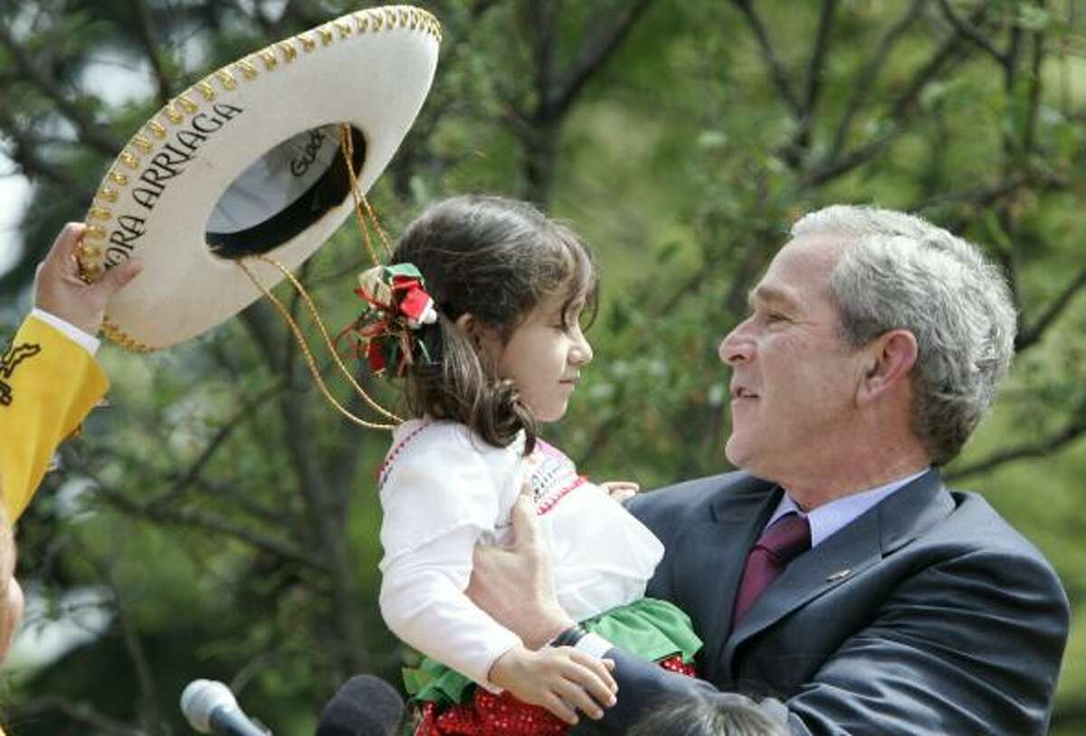 A young performer gets an assist in removing her sombrero before some face time with President Bush during a Cinco de Mayo celebration in the Rose Garden on Friday. The holiday is being masked by worries over immigration reform.