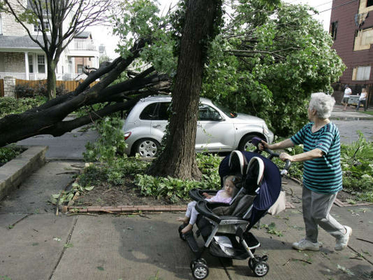 A woman passes a car crushed by a tree in Chicago on Friday.