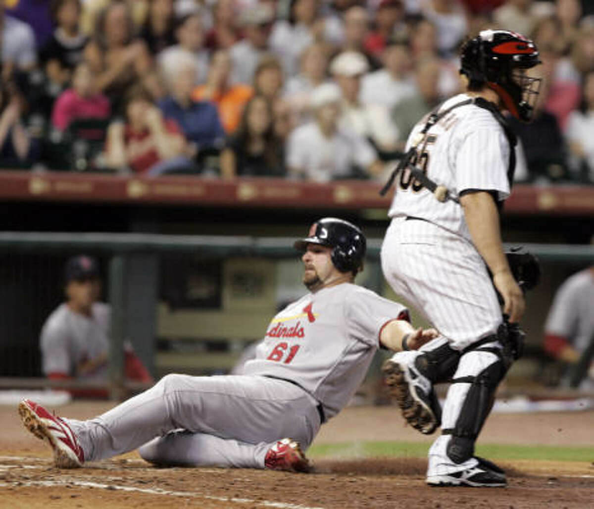 St. Louis's Nick Stavinoha, left, slides into home plate behind Houston Astros catcher Humberto Quintero (55) to score from third base on Ryan Ludwick's sacrifice fly to left field in the sixth inning.