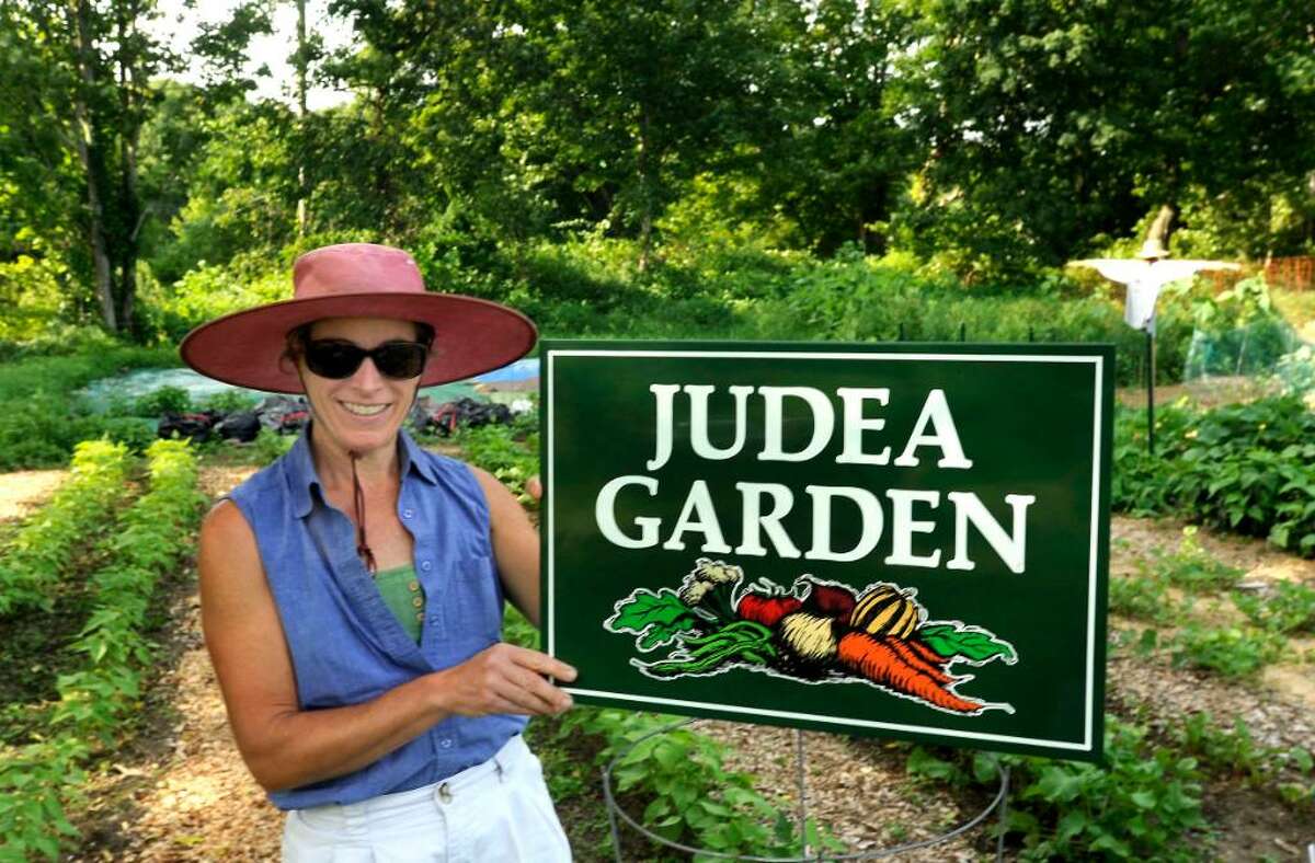 Denise Arturi, member of a ministry that grows produce which is donated to those who can't afford it, puts up a sign in the Washington garden they tend, on thursday.