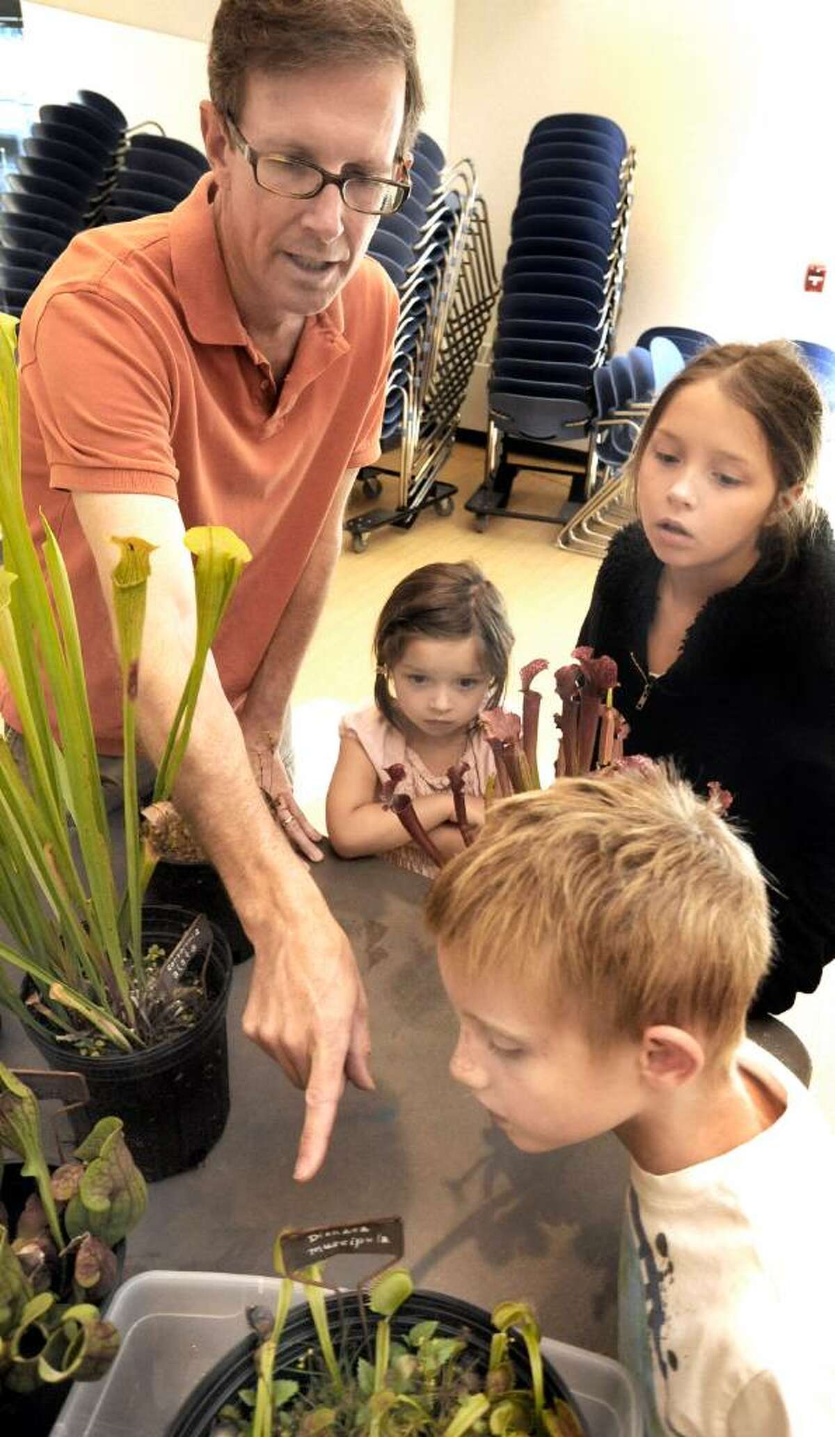 Plant specialist Matt Robey, of Redding, points out venus flytraps to Aidan Buss, 6, of Old Greenwich, and sisters Audrey, 5 and Eleanor DePalma, 10, of Ridgefield, during a program on carnivorus plants at the Ridgefield Recreation Center on saturday.