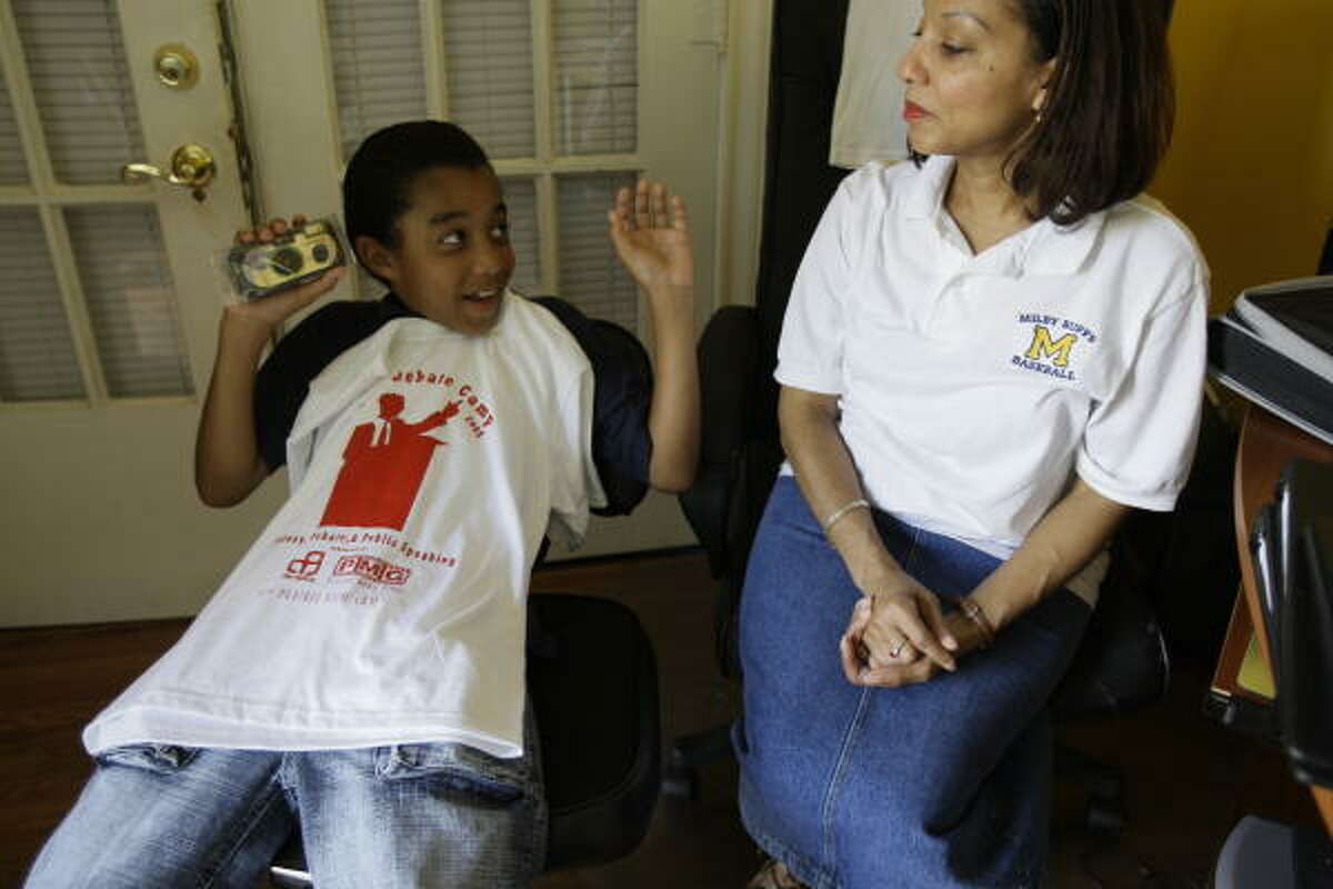 Debate camper Taylor Richardson shows off his new camp t-shirt and disposable camera to his mother, Chandra Richardson, during check before leaving for a week of Urban Debate Camp.