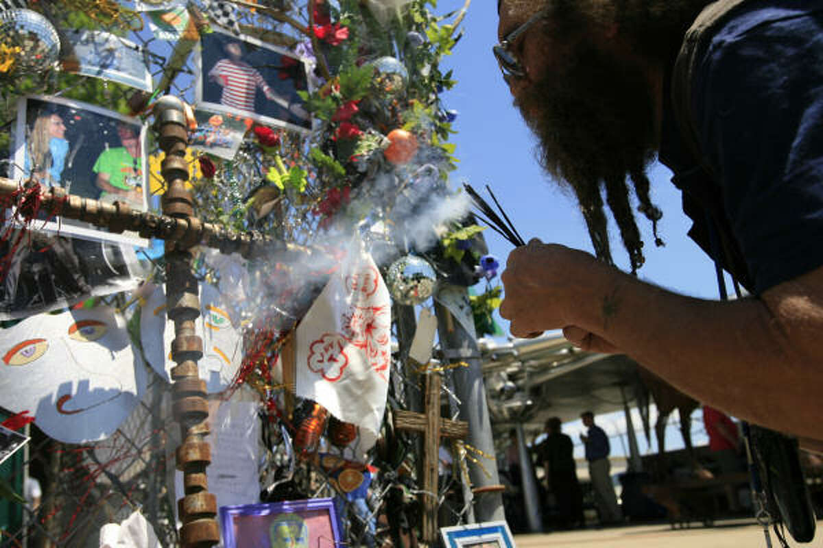 Jim Settles lights incense at an altar in memory of Tom Jones during a memorial for him at the Art Car Museum. Settles said he placed the incense inside a helmet he wore during the parade last week.