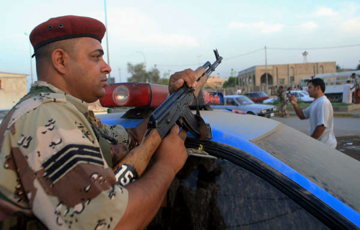An Iraqi police commando monitors a street in the southern city of Amara today.