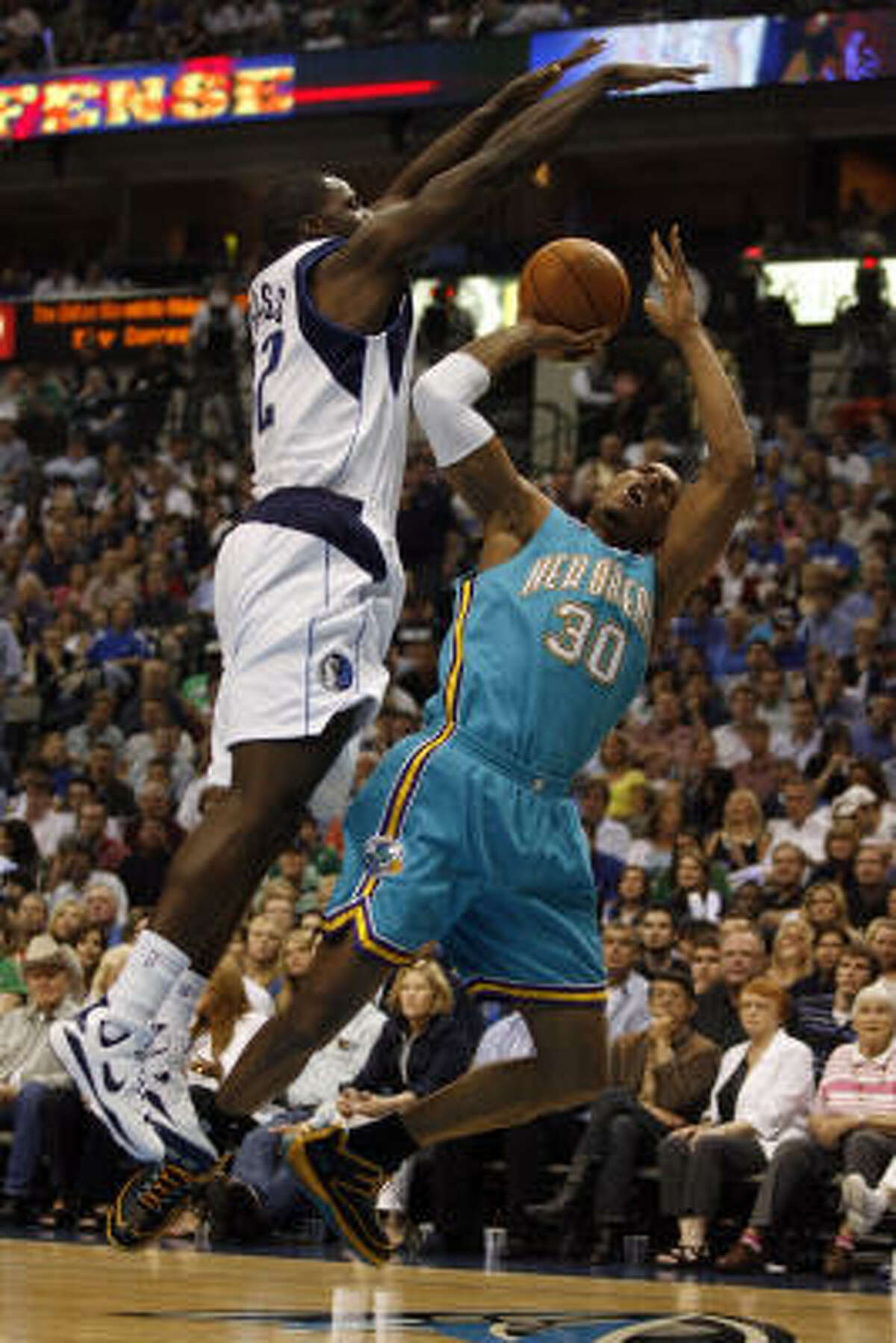 Hornets guard David West tries to shoot over the Mavericks' Brandon Bass in the early going.