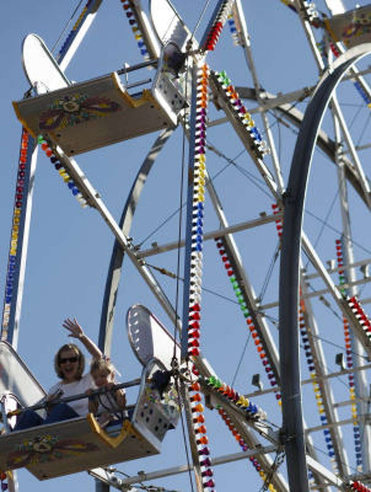 Angel Male, left, waving for a picture, and her daughter, Zoe, 3, both of League City, ride the Big Eli Ferris wheel at the Kids Country Kiddie carnival during The Houston Livestock Show and Rodeo Wednesday in Reliant Park.