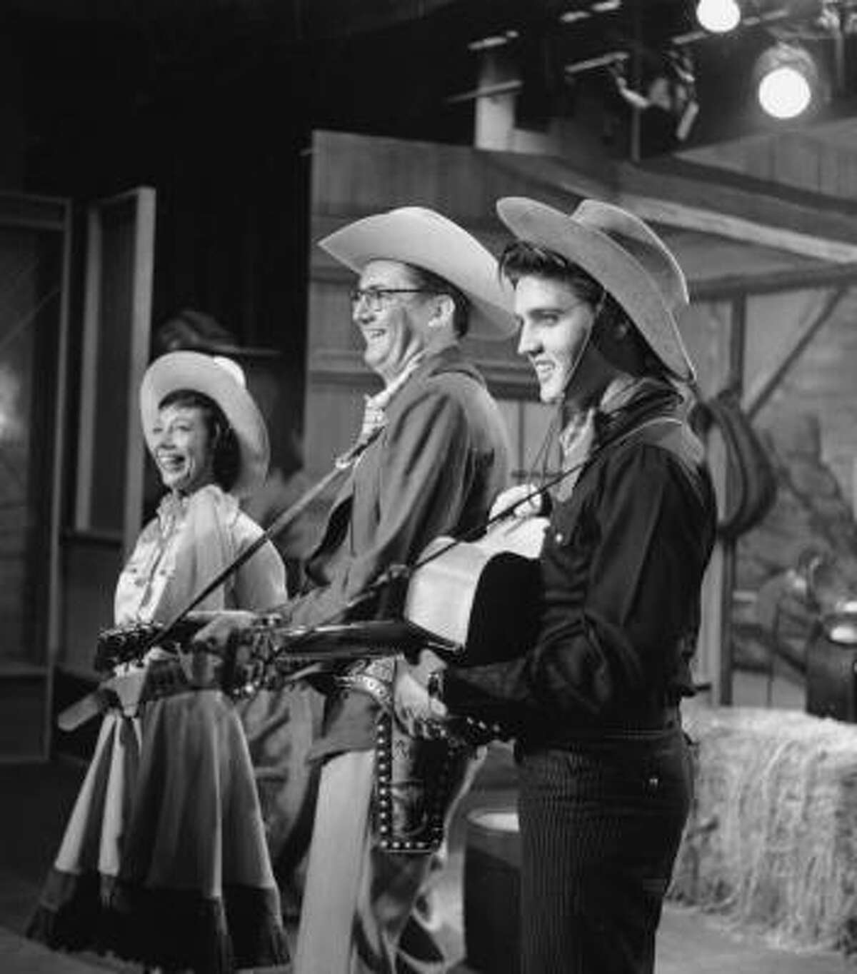 Elvis Presley is shown performing on the television program The Steve Allen Show in this July 1956 photo. At center is Steve Allen and to his right is Imogene Coca.