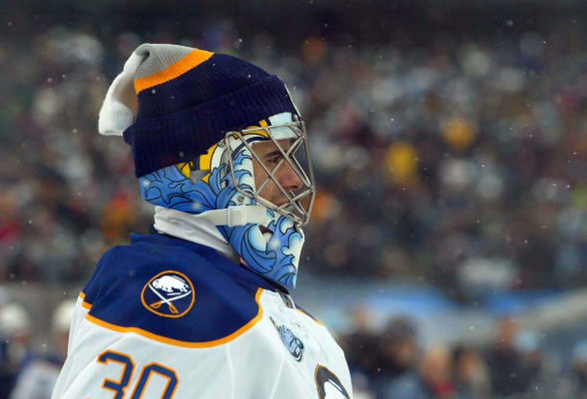 Buffalo Sabres goalie Ryan Miller attempts to stay warm with an extra cap while standing in front of his net.