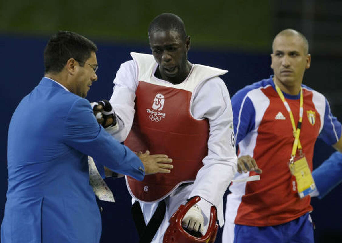 Cuba's Angel Matos (center) was disqualified Saturday in taekwondo after he was ruled the loser for taking too long for an injury timeout at his fight in Beijing. The decision set off an attack on the mat.