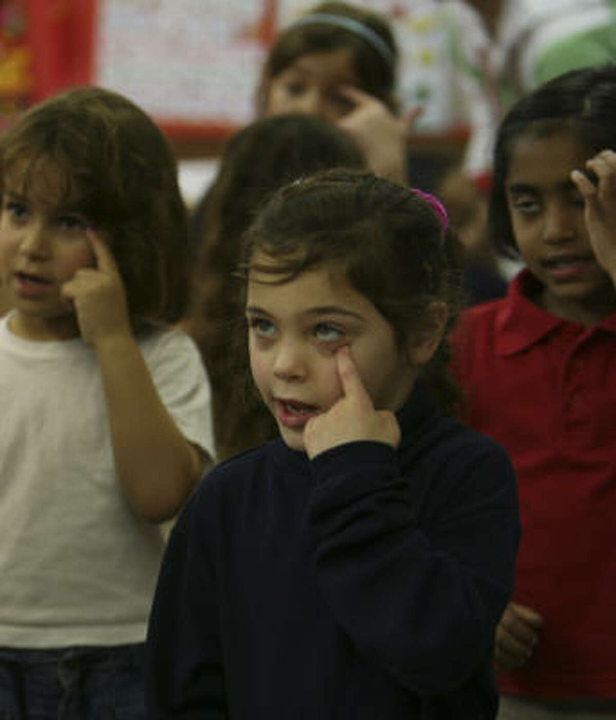 Sarah Mark, 6, and her classmates point to their eyes while singing about body parts.