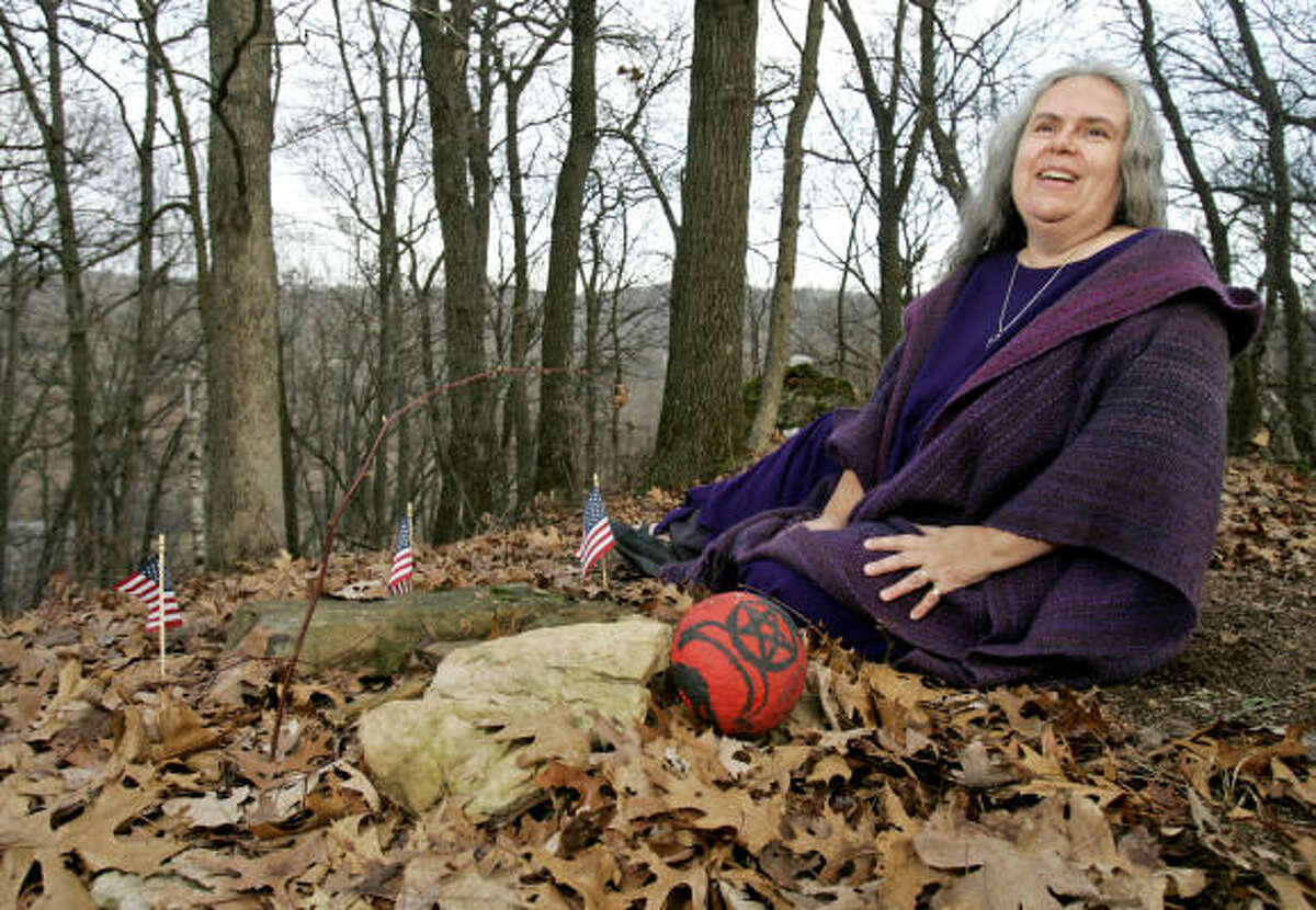 Selena Fox, a Wiccan priestess and founder of Circle Sanctuary, sits alongside the buried remains of a Korean War soldier near Barneveld, Wis. She and others sued the U.S. Department of Veterans Affairs over its ban on graveside pentacles at national cemeteries.