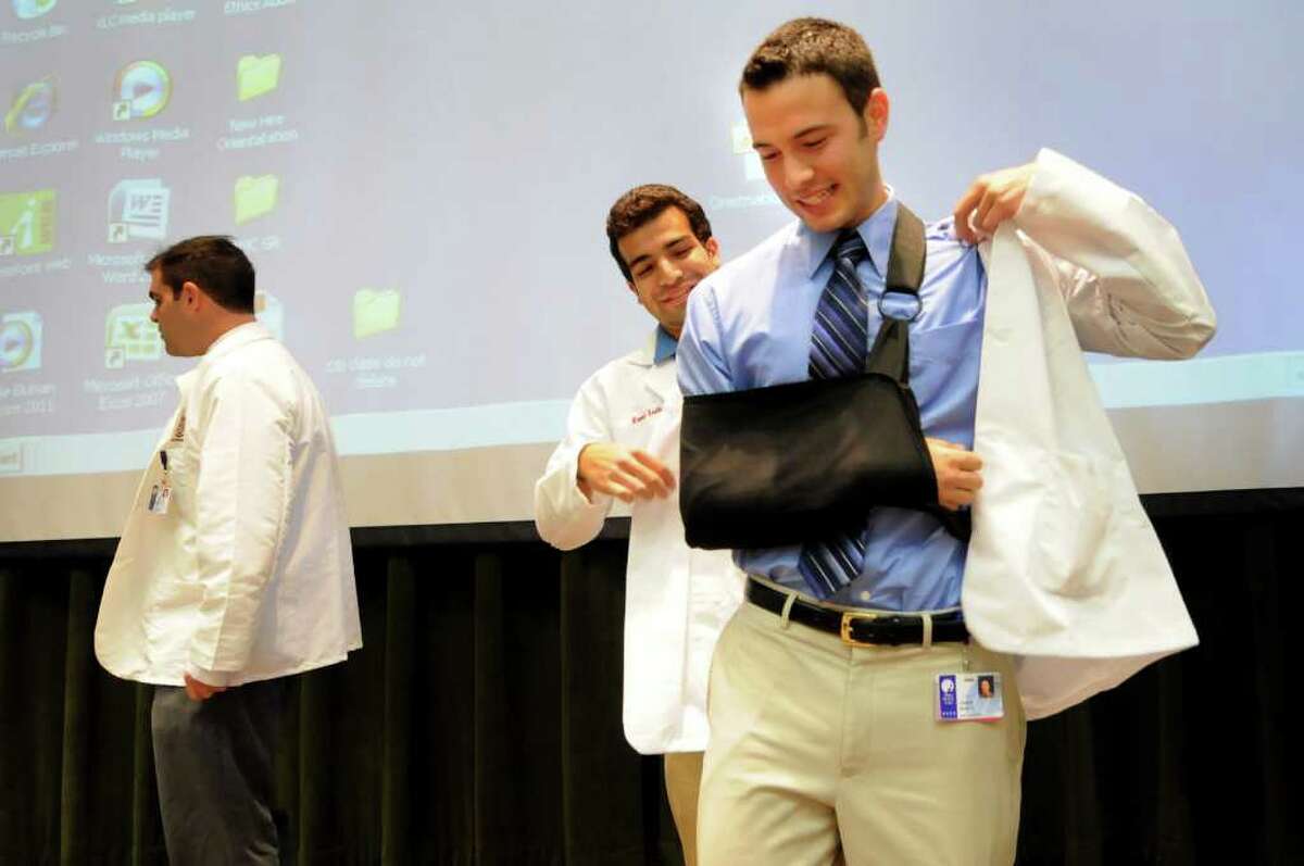 First-year medical student John Shultz of Altamont, right, gets initiated into the medical community as he puts on a white coat, with help from a second-year student, during the White Coat Ceremony on Thursday, Aug. 11, 2011, at Albany Medical College in Albany, N.Y. (Cindy Schultz / Times Union)