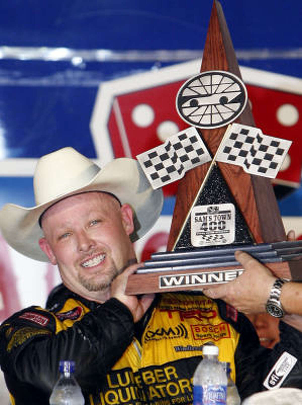 Todd Bodine holds the NASCAR Craftsman Truck Series Sam's Town 400 auto race trophy in victory lane following his win at Texas Motor Speedway on Friday.