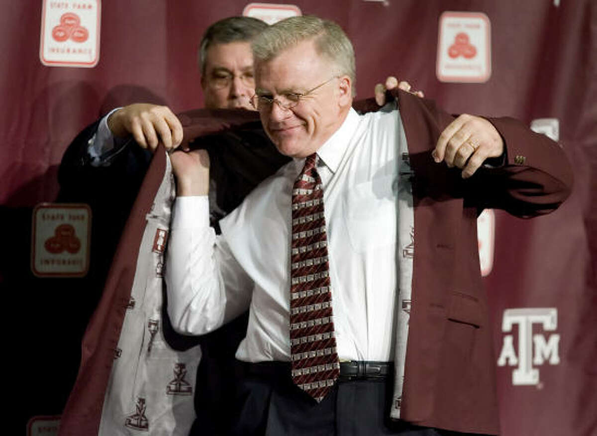 Texas A&M director of athletics Bill Byrne helps Mike Sherman put on his maroon jacket, customary of new Aggie coaches.