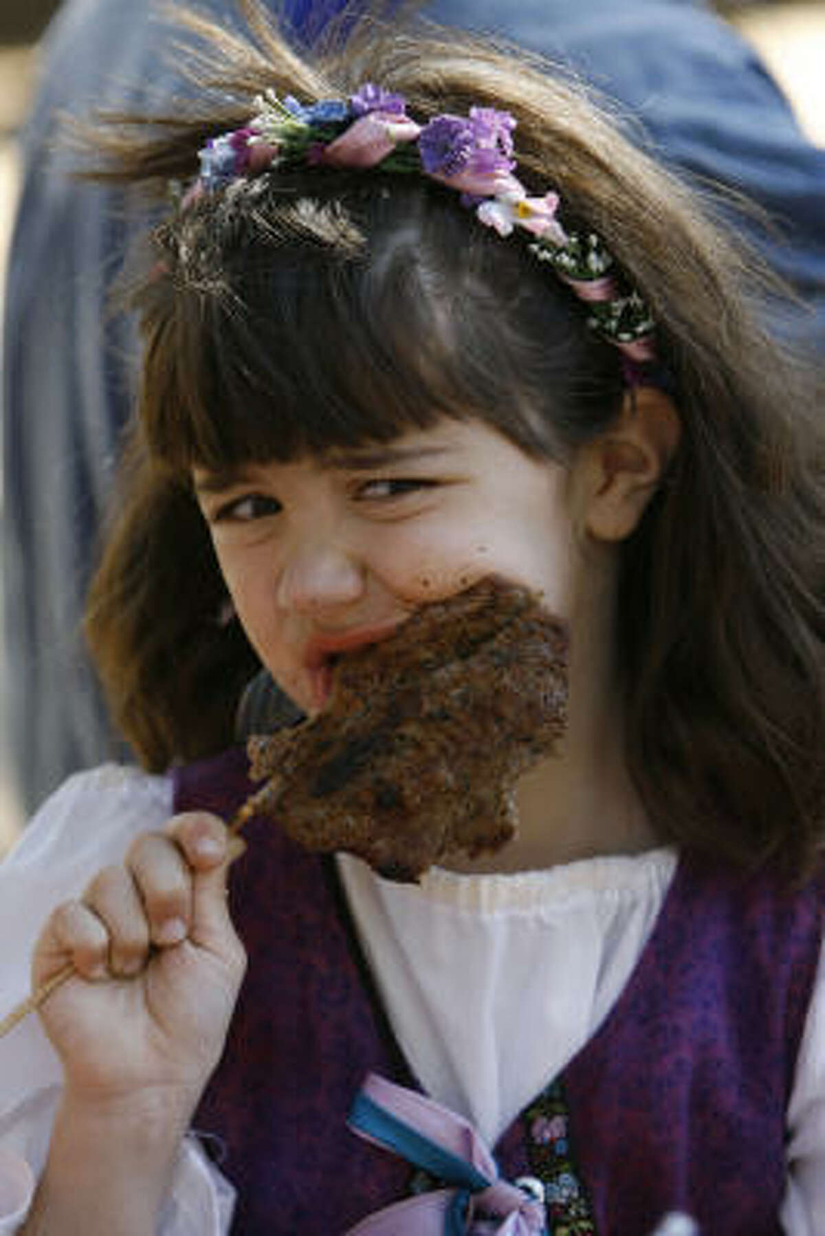 Regina Andrews, 7, of Missouri City enjoys a steak-on-a-stick during the Texas Renaissance Festival in Plantersville.