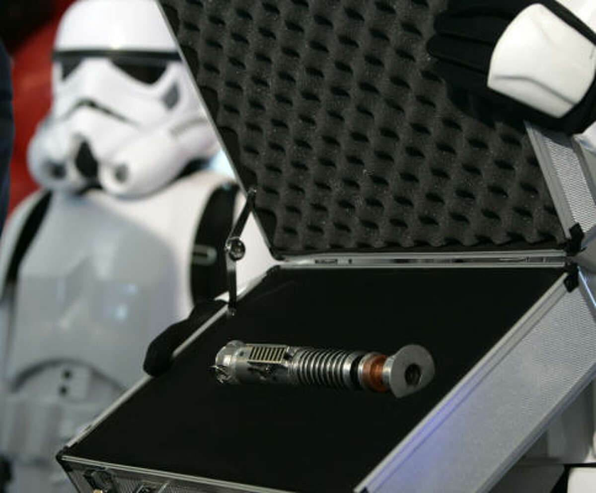 Luke Skywalker's original lightsaber is displayed by a Star Wars character.