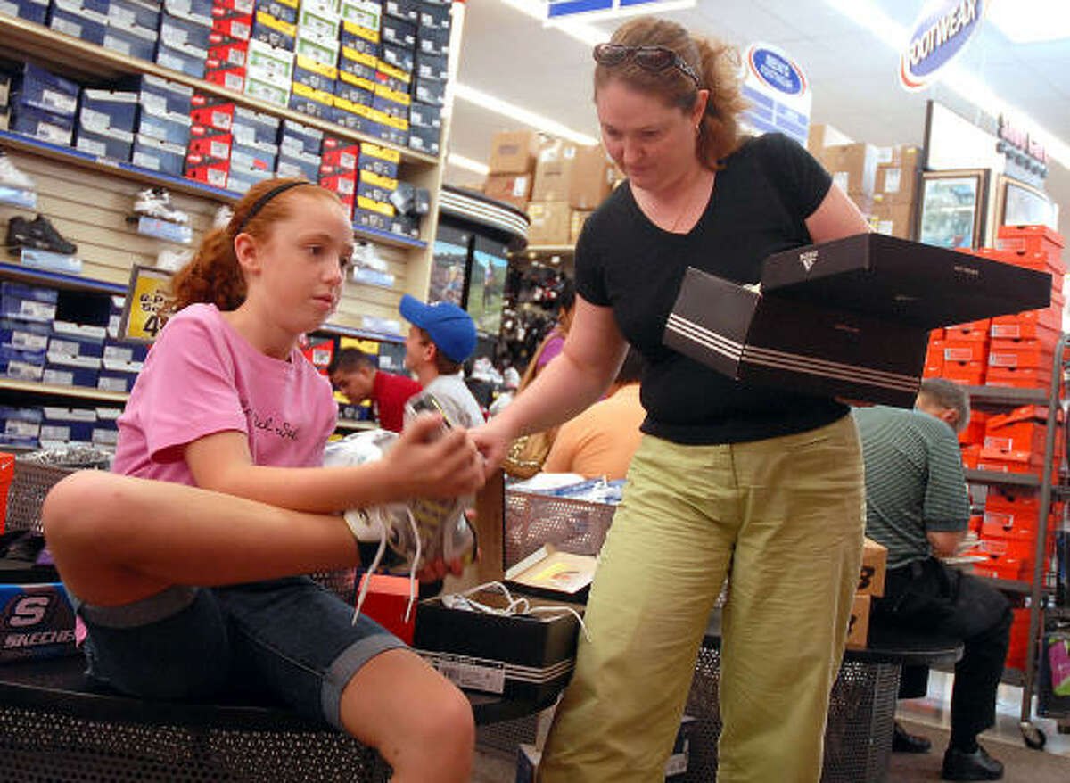 Catherine Ducote, 11, tries on shoes with her mother Elizabeth while shopping for school clothes at Academy on the Southwest Freeway during tax-free weekend Saturday.