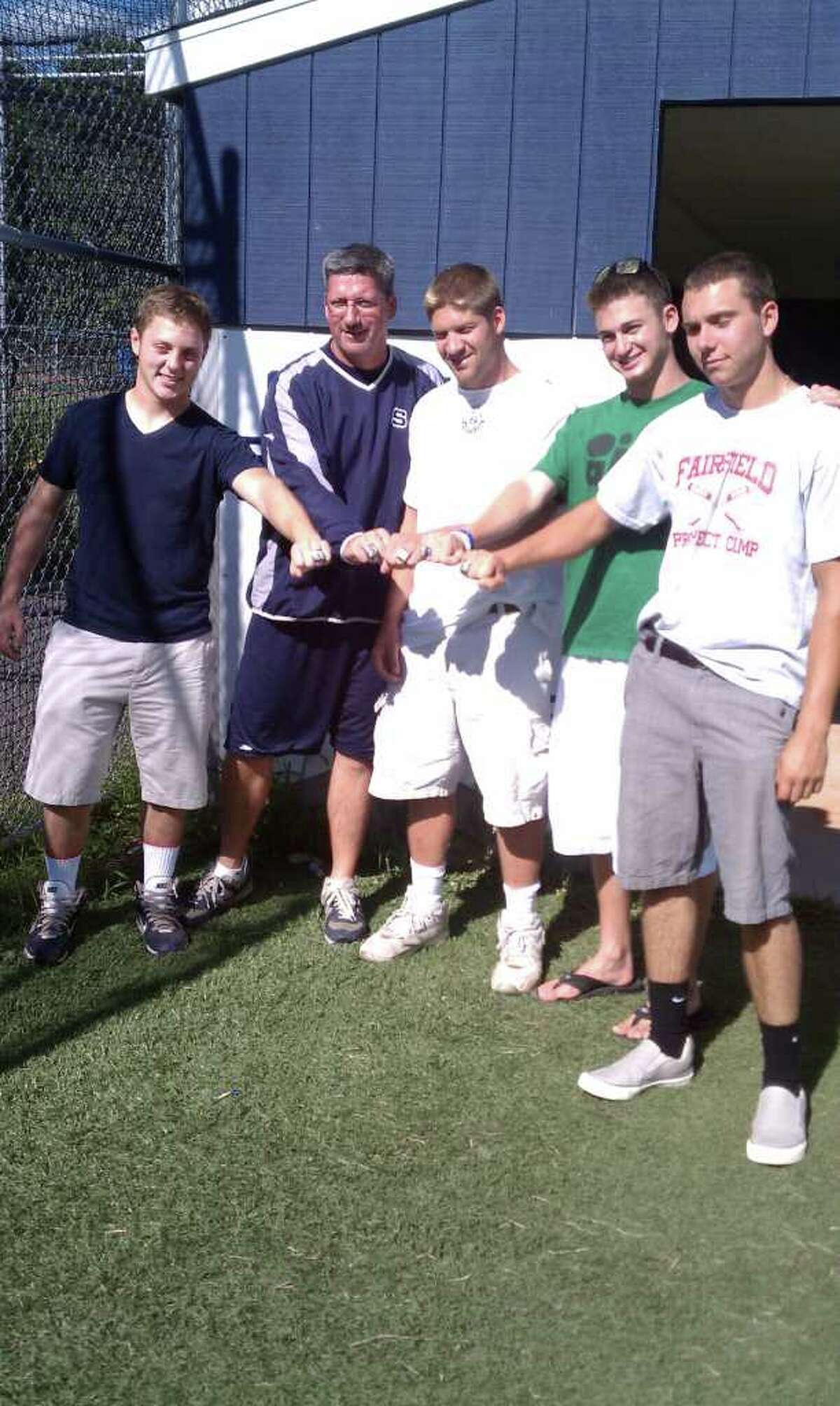 Staples baseball coach Jack McFarland, second from left, displays his 2011 FCIAC championship ring with four outgoing seniors, from left, Mike McGowan, Rob Gau, Brendan Bernstein and Chris Lametta.