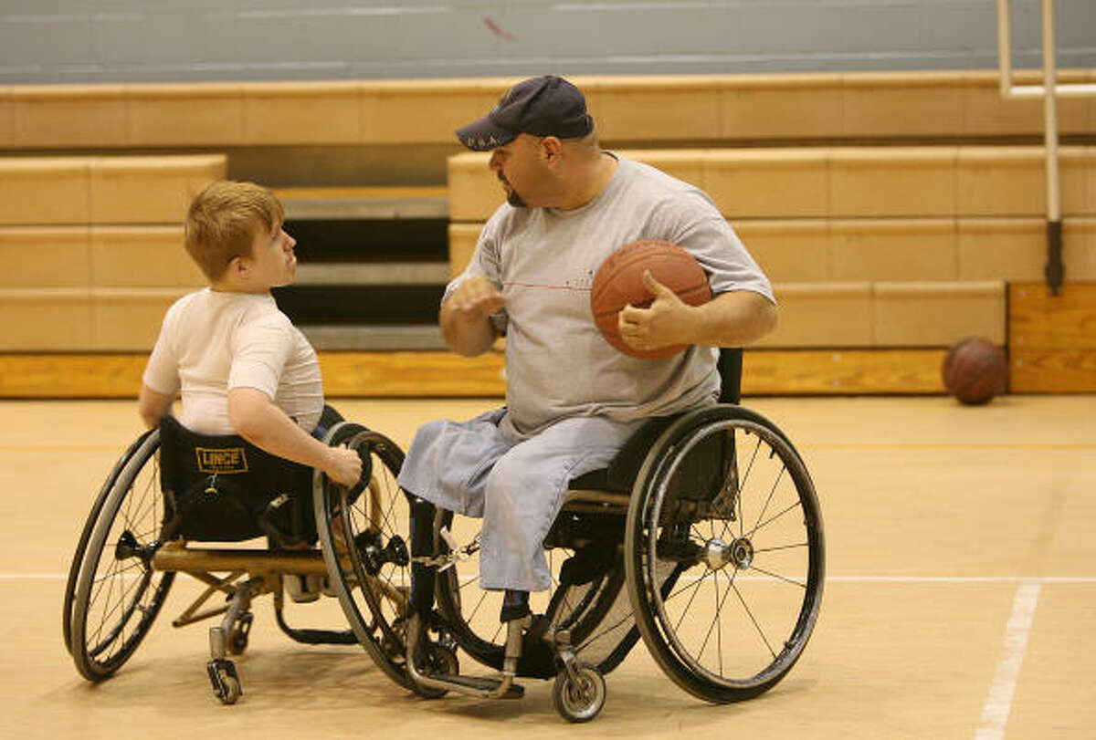 Coach Oziel Flores works withTrevor McCuiston, 15, who is a member of the young adult wheelchair basketball team. Flores coaches the team about basketball and about life.