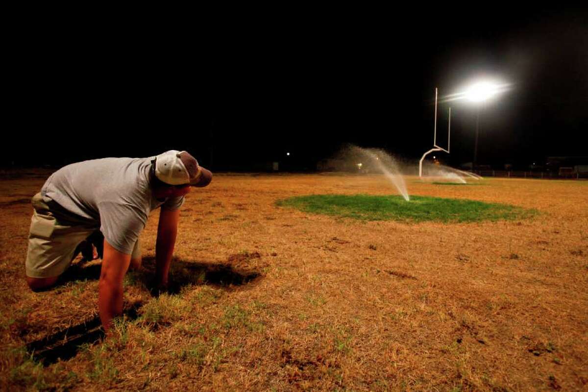 School Superintendent and Athletic Director for Robert Lee High School, Aaron Hood, adjusts the underground sprinkler system that is providing the life support for the school's' dried football field, Wednesday, Aug. 10, 2011, in Robert Lee. The school waters the field nightly, putting on over 6,000 gallons a day costing $200 per load of water that is trucked in from a neighboring city. "We take pride in our field, but it's also a matter of safety," Hood said. "Not only for out team but for other teams when they visit, they need a semi-soft spot to fall." The city of Robert Lee is experiencing an unprecedented drought receiving around 3 inches of rain in the past year. The city's drinking water is nearly dried up coming from the local Lake E.V. Spence which is at .7% capacity. Families have been forced to conserve water cutting back from 20,000 gallons per family per month to 3,000 to 4,000 gallons. If the city continues to receive no significant rain fall, the city will run out of water by early 2012. ( Michael Paulsen / Houston Chronicle )