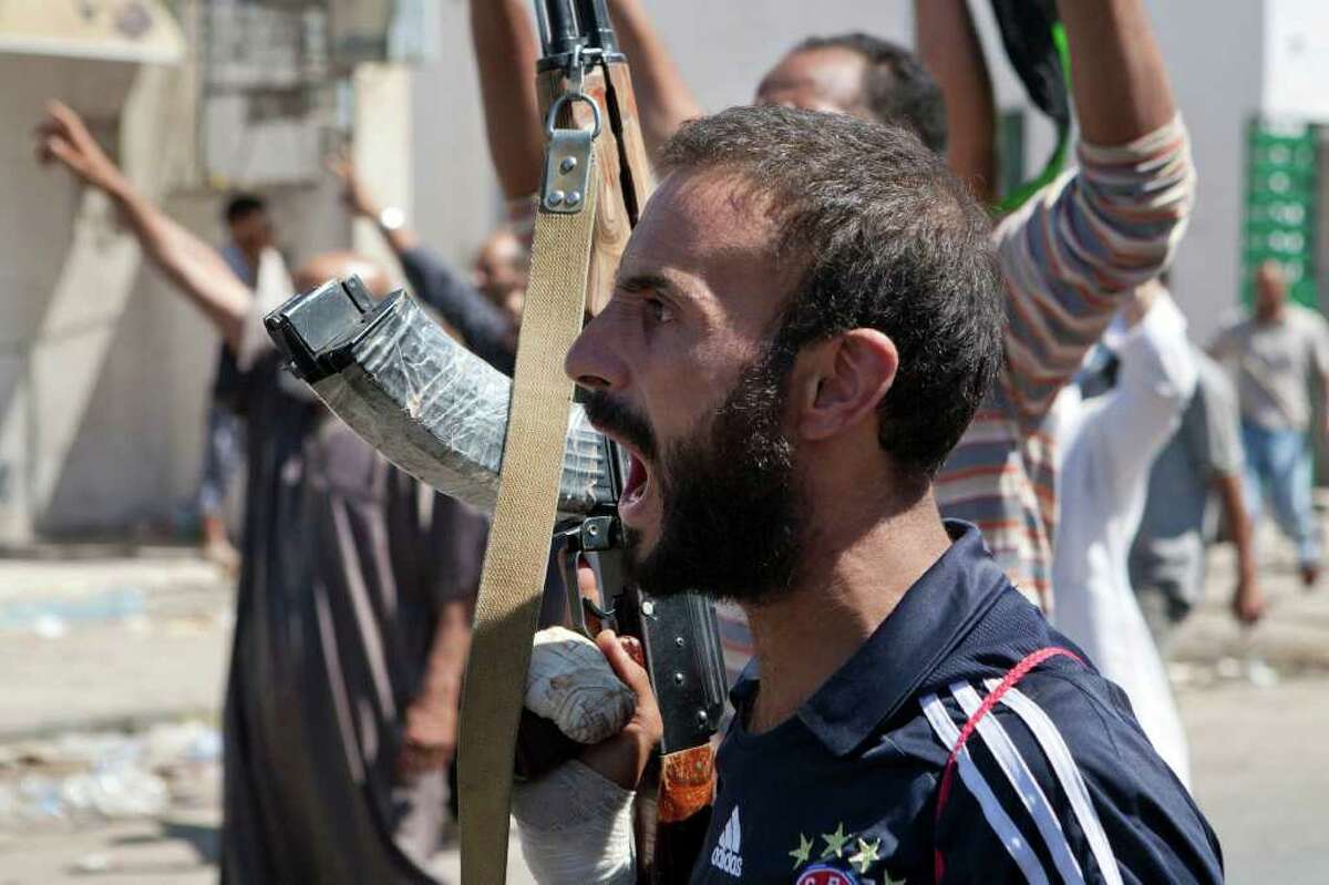 In this Sunday, Aug. 14, 2011 photo, a Libyan rebel fighter in Zawiya, western Libya, reacts to the news that the city of Surman, an important strategic point, is now under the control of the rebel forces. Libyan rebels have claimed they were trying to cut off two key supply routes to Moammar Gadhafi's stronghold in Tripoli after capturing more towns in the west of the country. On Sunday, the opposition fighters also battled government forces for control of the strategic city of Zawiya, just 30 miles (48 kilometers) from the capital, Tripoli. (AP Photo/Giulio Petrocco)