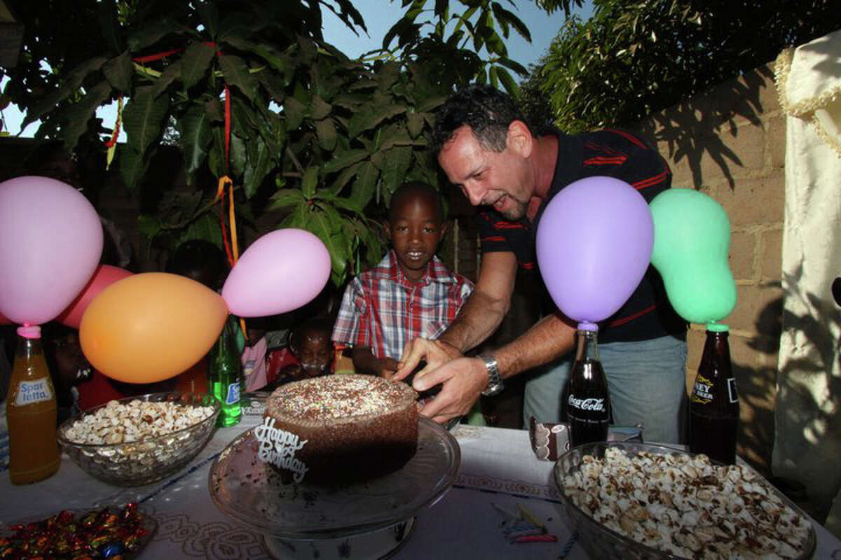 Gary Glick, medical director of the Circle Care Center in Norwalk, cuts the cake during his godson Tichaona Gary's surprise ninth birthday party in July in Zimbabwe.