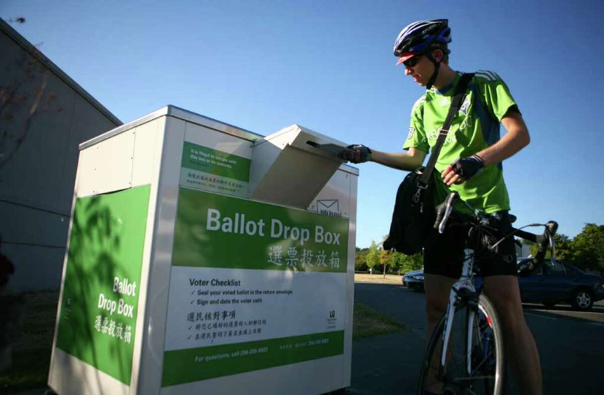 Jonathan Kamrath drops off his ballot and his wife's ballot at the Magnuson Park ballot drop box.