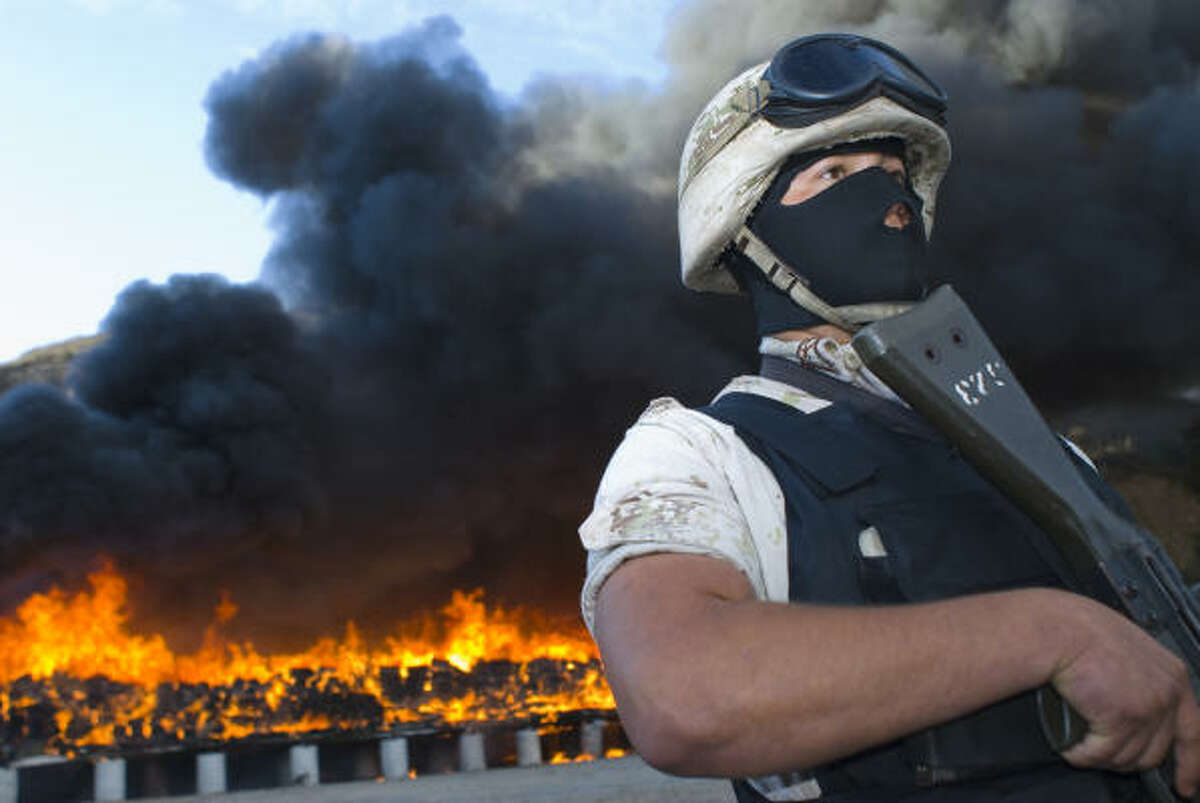 A soldier stands guard in October as officials burn tons of marijuana in Tijuana, Mexico. Pot sales finance the gangster warfare that has killed more than 40,000 Mexicans.