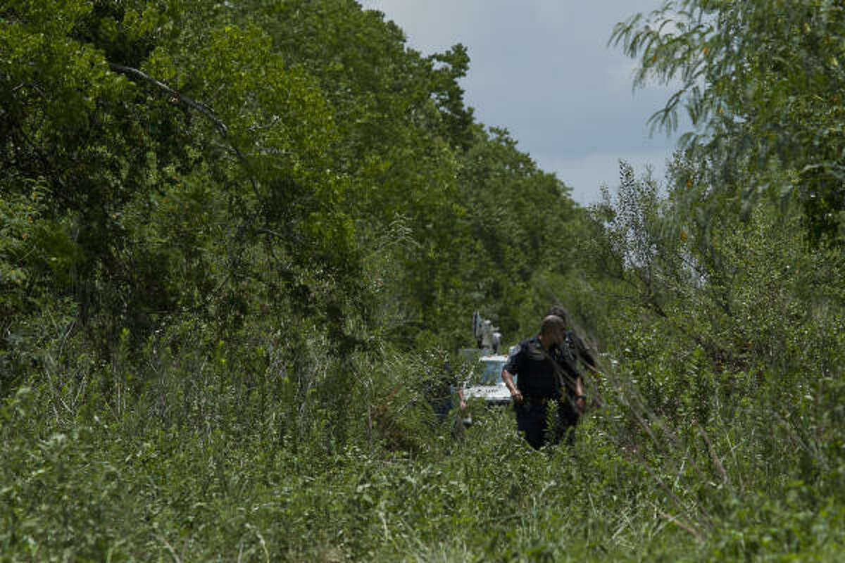 Police officers walk out of the wooded area across from Clear Creek High School in League City on Monday, where a Technical Rescue Unit worked to free 25-year-old Kevin Gonterman.