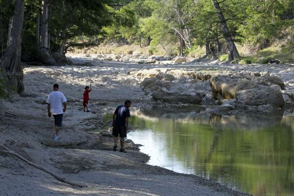 Residents scan for stranded fish in one of the few remaining pools left on the upper Guadalupe River, near FM 311 and the River Point subdivision in Comal County.