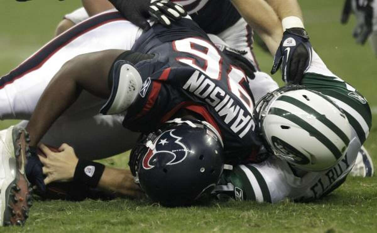 Texans defensive end Mark Anderson, left, recovers a fumble by Jets quarterback Greg McElroy during the first half.