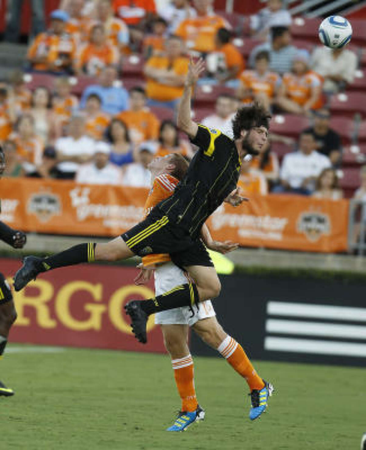 Columbus' Tommy Heinemann (32) battles for the ball against the Dynamo's Andre Hainault. Hainault makes his first start since April due to his participation with Canada in the Gold Cup.