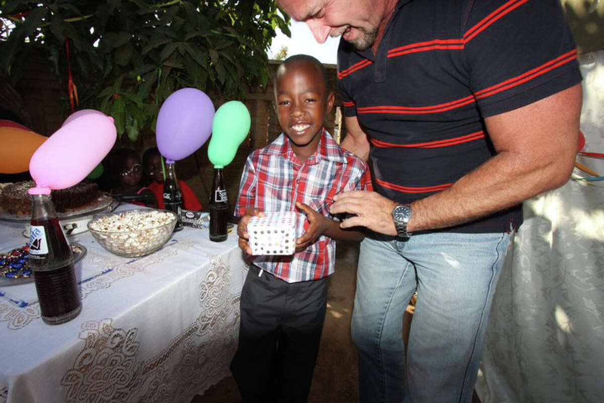 Gary Glick, medical director of the Circle Care Center in Norwalk, gives his godson Tichaona Gary a present during a surprise ninth birthday party in July in Zimbabwe.