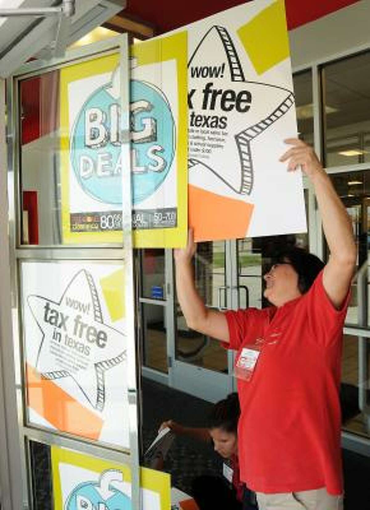 Fran Atchison posts a tax-free sign at the JC Penney in Katy.