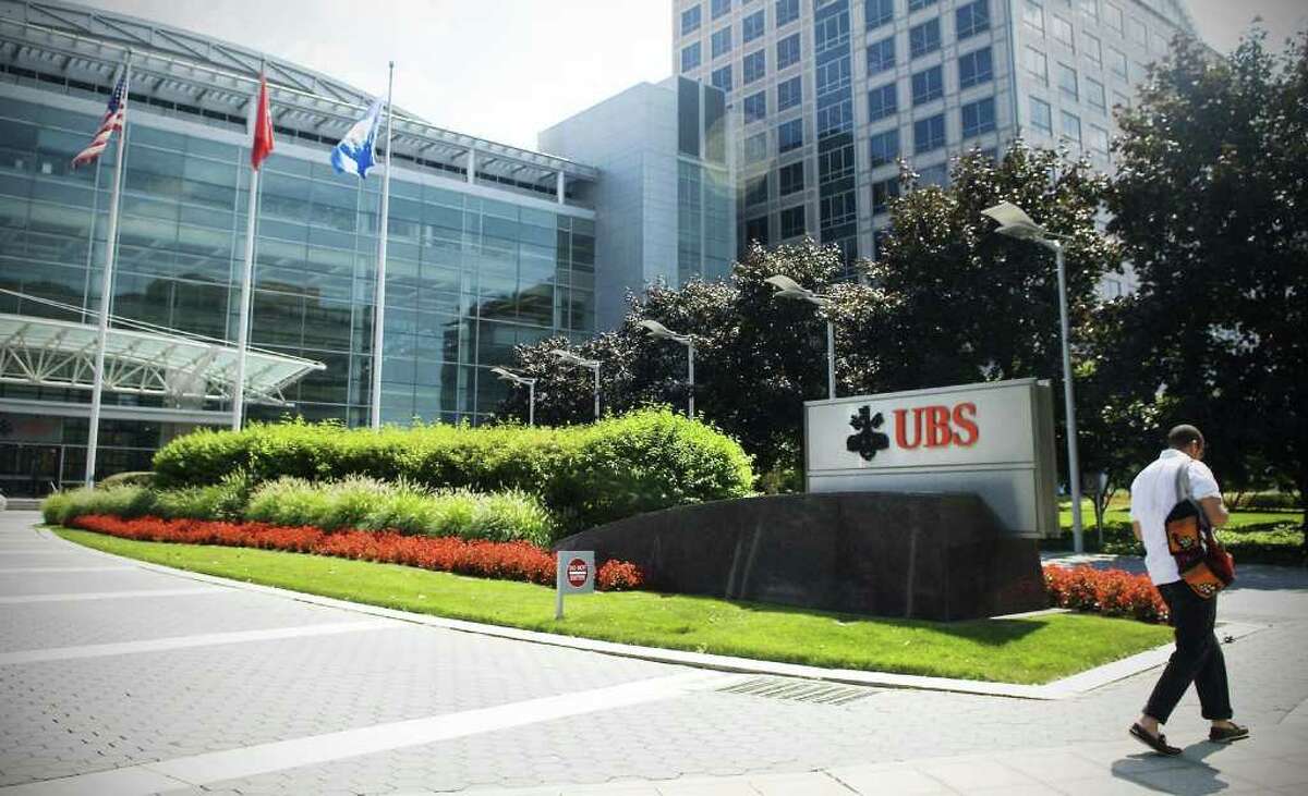 A pedestrian walks by the UBS North American headquarters in Stamford, Conn.