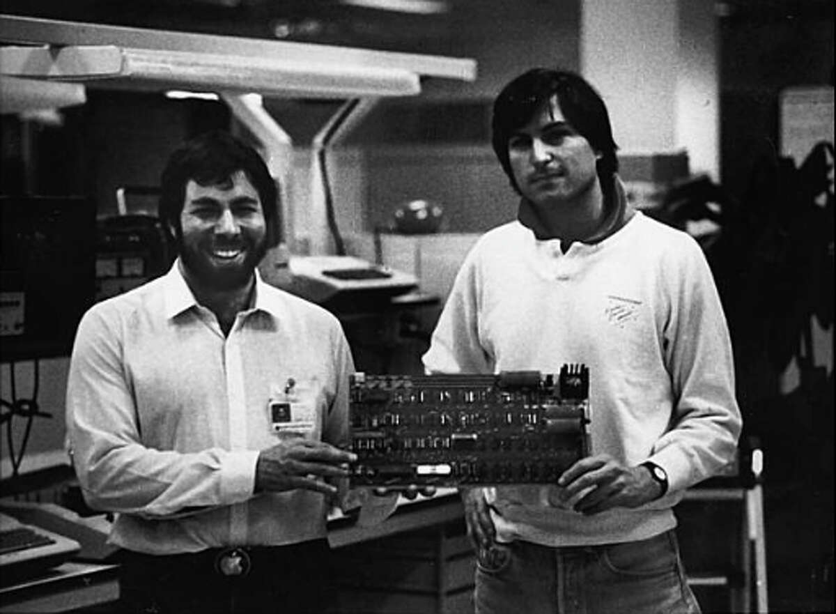 Steve Wozniak and Steve Jobs, co-founders of Apple Computer, with one of the original Apple I computer circuit boards.