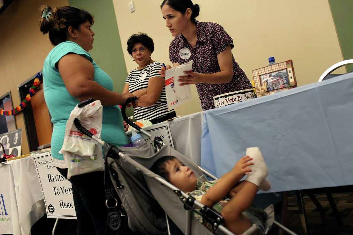 Sarah Linares, right, Field Manager with the Southwest Voter Registration Education Project, registers Debra Hernandez, left, to vote while her son, Jeremiah Gomez, 1, waits during CentroMed's Back-to-School Health Assessment and Resource Fair at Southside Clinic on Saturday, August 6, 2011. Looking on is volunteer Maria Davalos-Salinas, center.